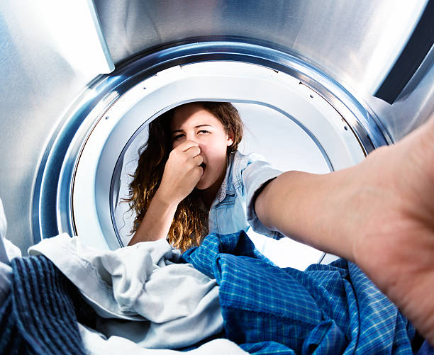istock Woman taking clothes from drier holds nose, horrified by smell 520664465
