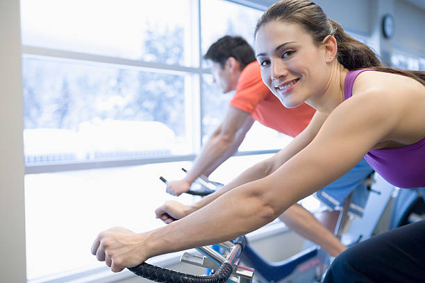 istock Man and woman using exercise bikes in gym 520664575