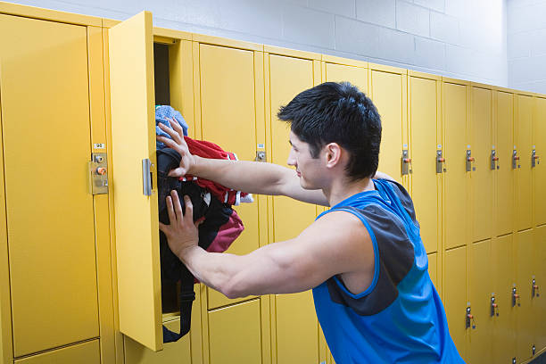 istock Man in locker room, putting clothes into locker, side view 520665511