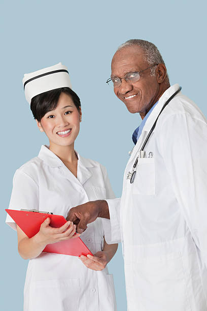 Doctor working Portrait of happy medical professionals having a discussion over medical report against light blue background vietnamese old man portrait stock pictures, royalty-free photos & images