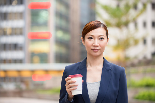 Attractive Chinese woman drinking coffee in the Hong Kong financial district.  Hong Kong iStockalypse.