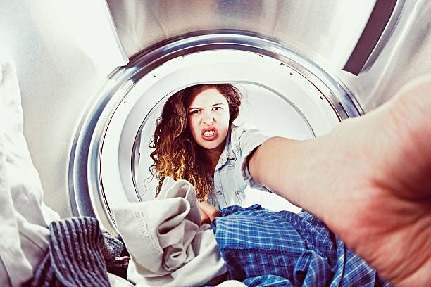 istock Seen from inside clothes drier, young woman reaches in, grimacing 520688785