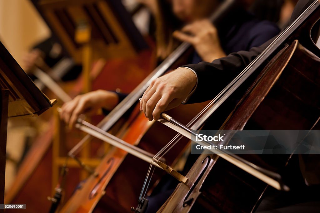 Hands of the man playing the cello Hands of the man playing the cello in dark colors Orchestra Stock Photo