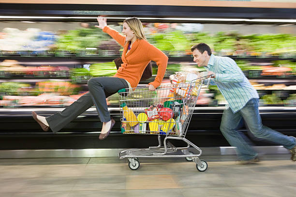 uomo spingendo donna in supermercato trolley, immagine mossa - couple romance running freedom foto e immagini stock