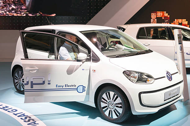 Brussels, Belgium - Januari 12, 2016: WhiteVolkswagen E-Up electric compact city car at the VW stand. Two men are sitting indside the car. The car is on display during the 2016 Brussels Motor Show. The car is displayed on a motor show stand, with lights reflecting off of the body.
