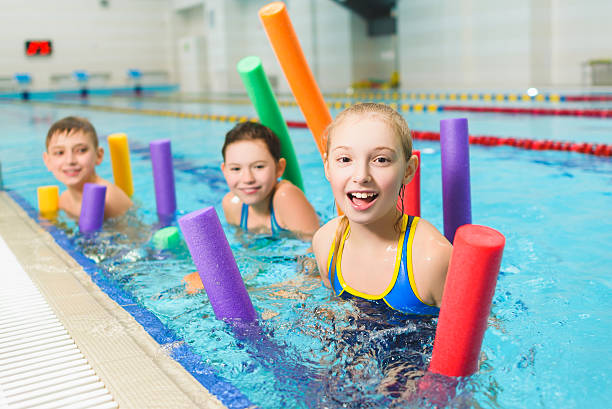Happy and smiling group of children learning to swim with stock photo