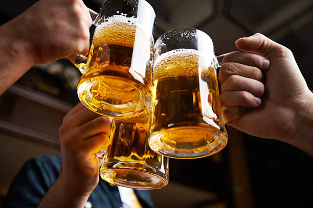 Beer toast Hands of three men toasting with beer glass of beer stock pictures, royalty-free photos & images