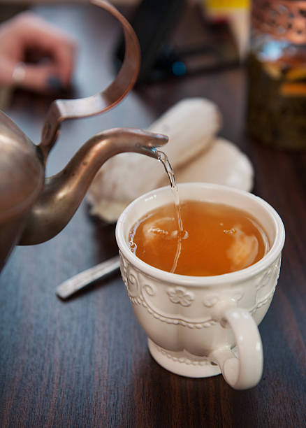 istock Old-style copper kettle pouring tea to white cup 520705584