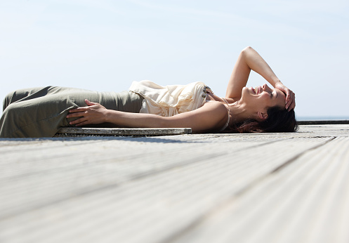 Portrait of a young woman lying down and laughing outdoors