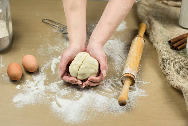 istock Closeup of female baker's hands kneading dough in bakery. 520710042