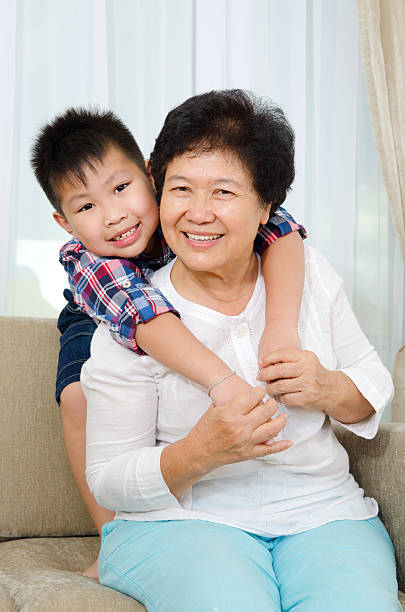 Cheerful moment featuring Asian grandparents and their grandson sitting on sofa at home.