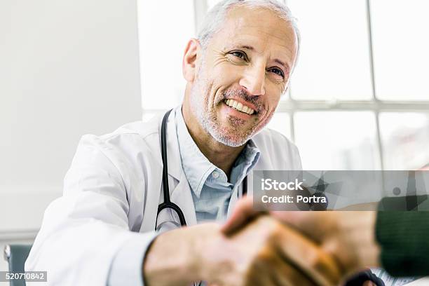 Confident Doctor Shaking Hands With Patient Stock Photo - Download Image Now - Doctor, Handshake, Patient