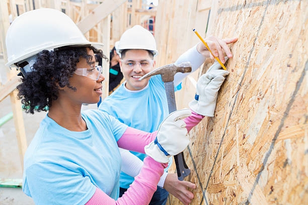 Female volunteer uses hammer at home construction site