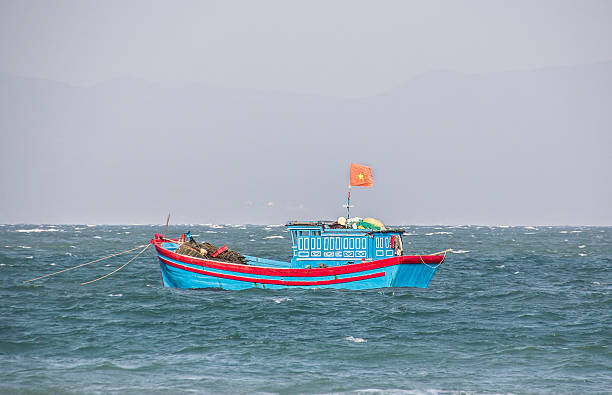 vietnamese fisherboat, Doc Let, Vietnam - February 7, 2016: A vietnamese fisherboat at Doc Let near Nha Trang, Vietnam. The fisherboat has the red vietnames flag hoisted. flaglets stock pictures, royalty-free photos & images