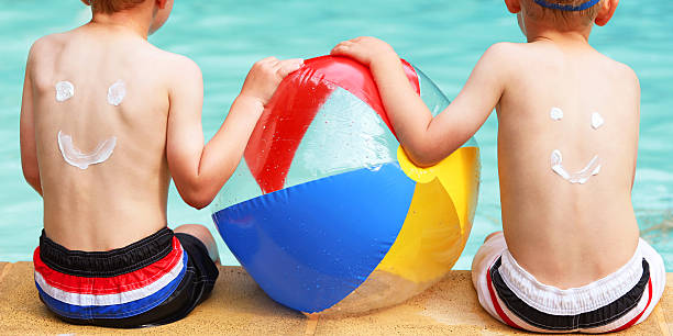les enfants avec crème solaire smileys sur le dos de la piscine - beach ball swimming pool ball child photos et images de collection