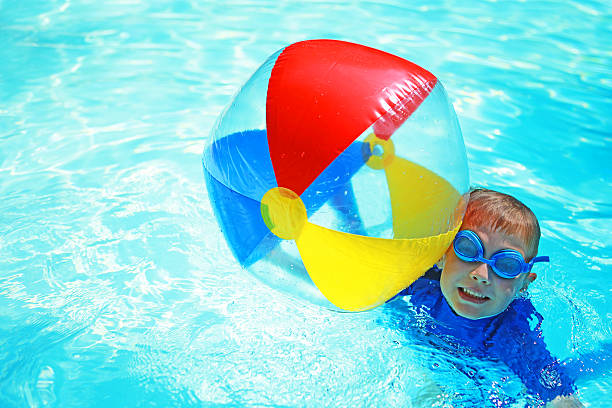 enfant tenant coloré de ballon de plage de la piscine - beach ball swimming pool ball child photos et images de collection