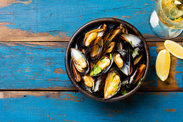 Mussels in clay bowl, glass of white wine and lemon stock photo