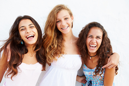 Portrait Of Three Teenage Girls Leaning Against Wall  Smiling To Camera
