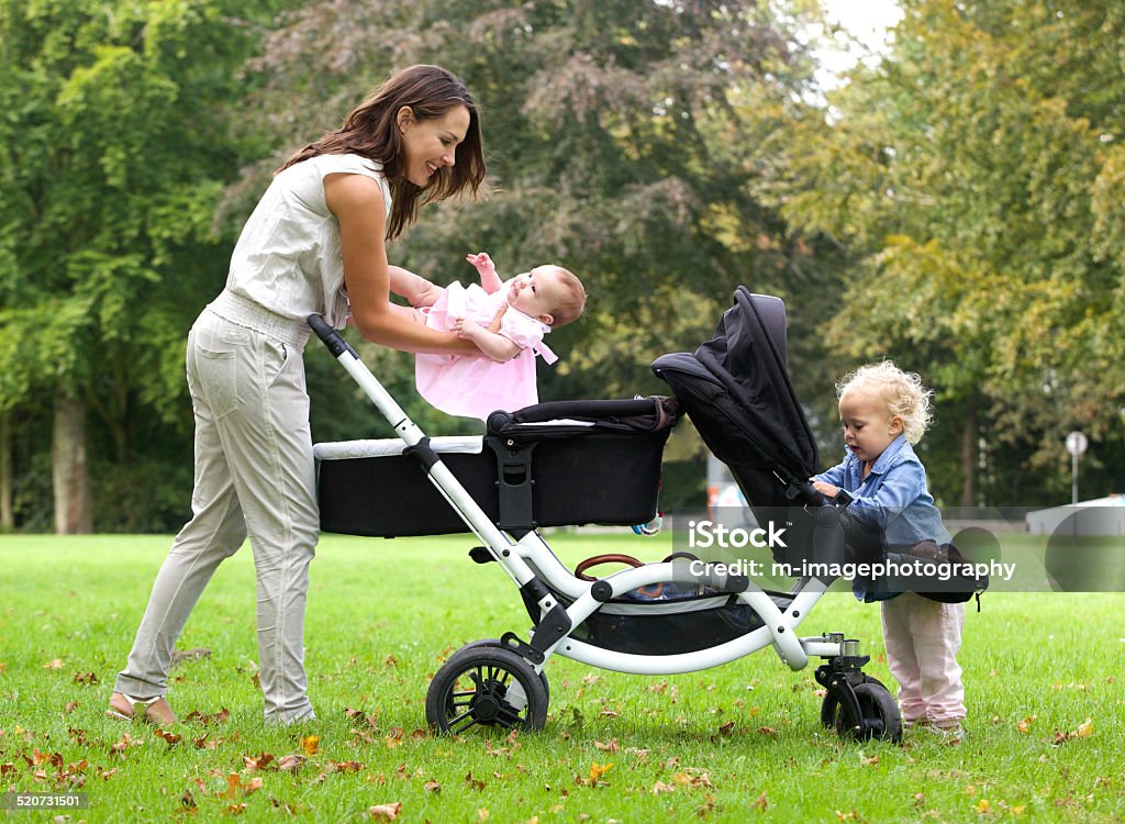 Mother and daughters with pram outdoors Portrait of a mother and daughters with pram outdoors Baby Carriage Stock Photo