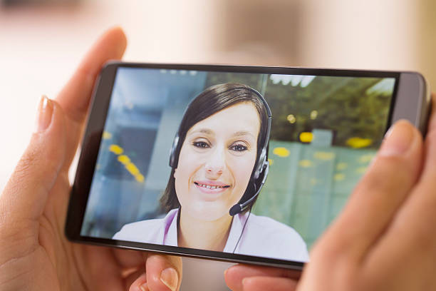 feminino mão segurando um telefone inteligente durante um skype vídeo - skype - fotografias e filmes do acervo