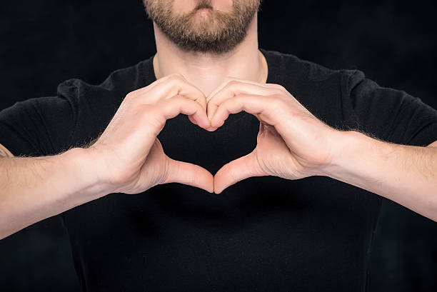 istock Man in a black shirt showing hand gesture heart 520733364
