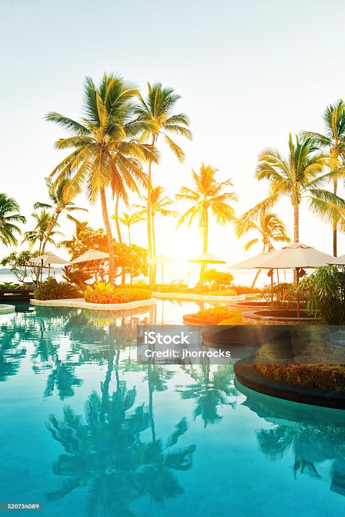 Tropical Resort Poolside at Sunset Outdoor pool area at a tropical resort during sunset. Vacations Stock Photo