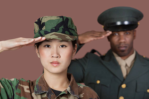 Solid portrait Portrait of young female Marine Corps soldier and male officer saluting over brown background black military man stock pictures, royalty-free photos & images