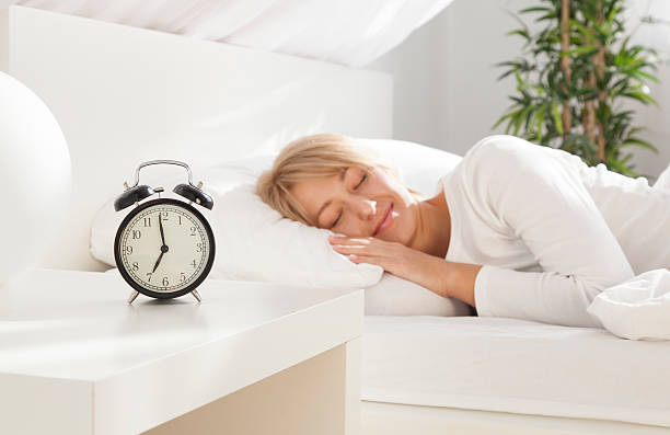 beautiful girl sleeping in her bed.  focus on clock