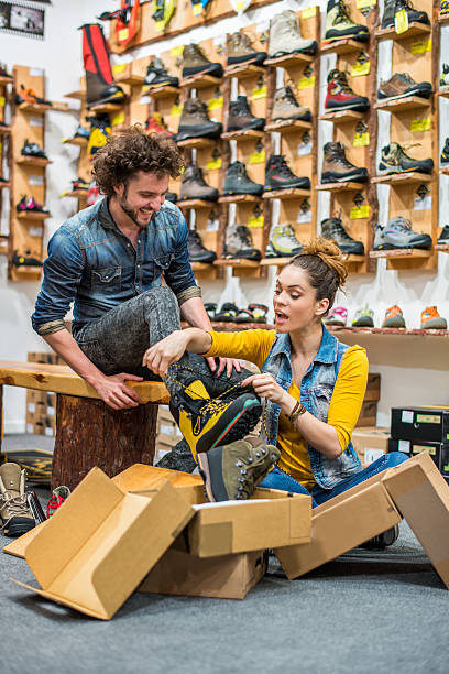assistente di negozio, aiutando il cliente a provare scarponcini da hiking - shoe store sales clerk customer foto e immagini stock