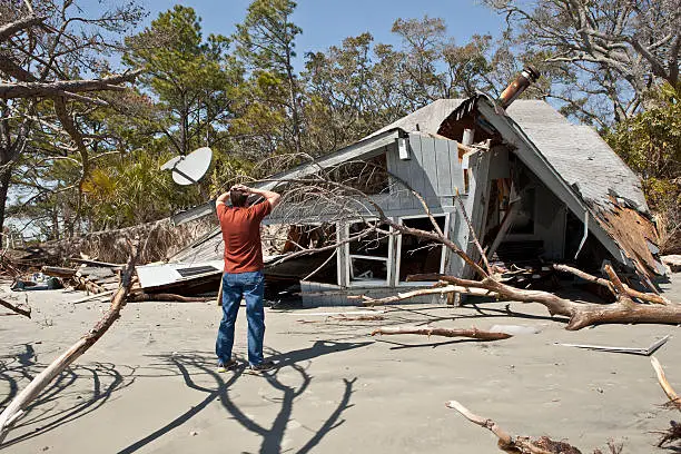 man grieving over house destroyed in flood.