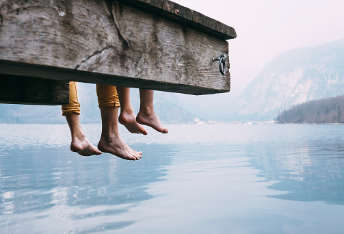 Father and son swung their legs from the wooden pier on mountain lake