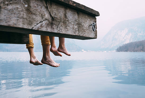 Father and son on wooden pier on mountain lake Father and son swung their legs from the wooden pier on mountain lake moored photos stock pictures, royalty-free photos & images