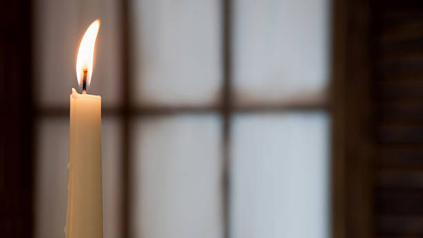 White high burning candle on a blurred background of  window