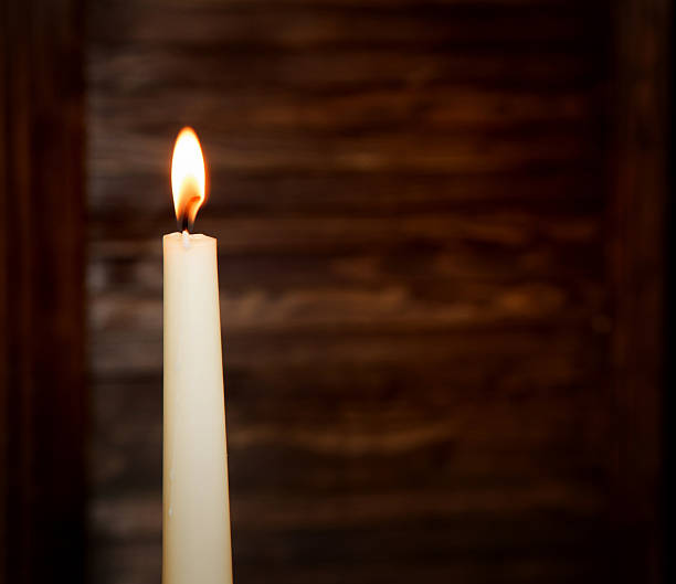 istock White high burning candle on a blurred wooden background 520741284