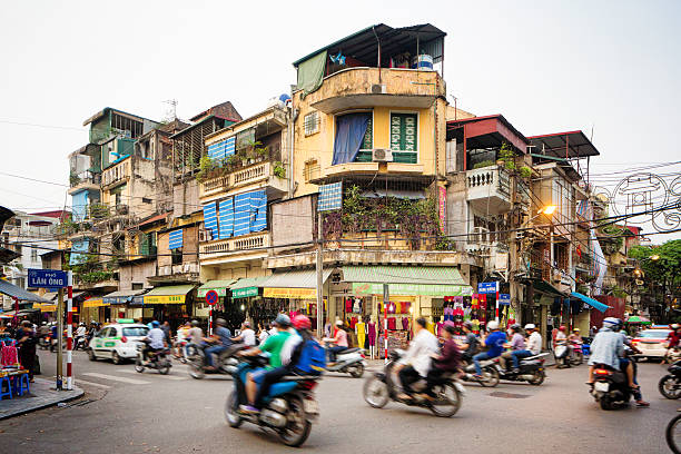Busy street corner in old town Hanoi Vietnam Busy street corner in old town Hanoi, Vietnam. Lots of people are commuting on motorbikes or cars. The street is lined by stores and appartment buildings. editorial stock pictures, royalty-free photos & images