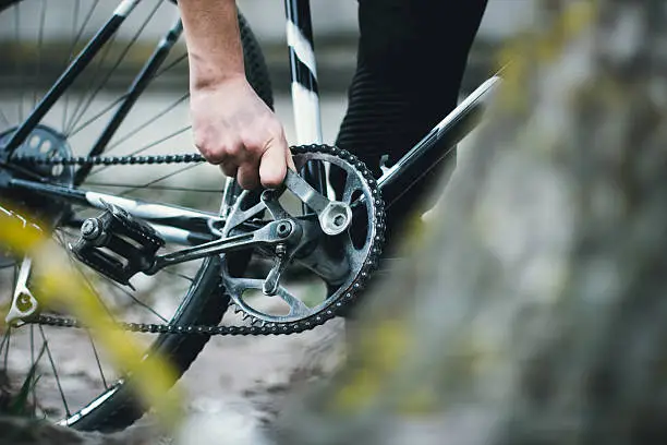 man repairing a bicycle with a wrench in the forest