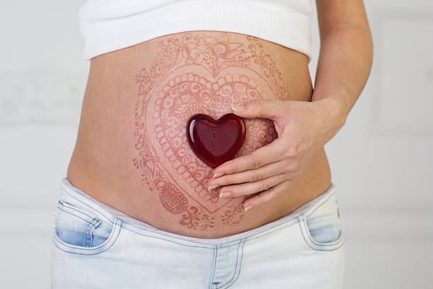 Woman's pregnant belly with henna tattoo stock photo