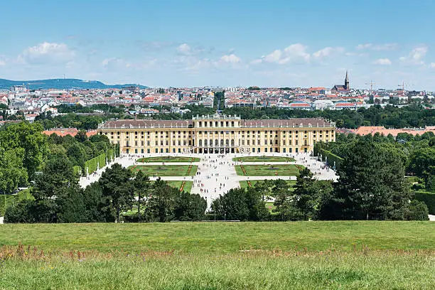 Elevated view of Schönbrunn Palace in Vienna, with the city's skyline in the background. This Palace is the former imperial summer residence in Austria, one of the most important monuments and major tourist attractions in the city.