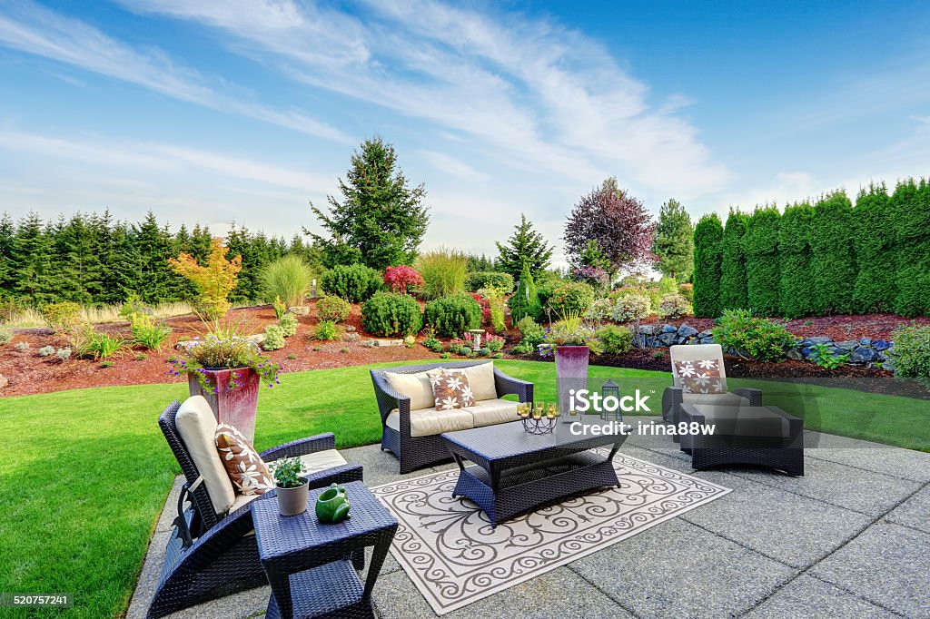 Impressive backyard landscape design with patio area Impressive backyard landscape design. Cozy patio area with settees and table Yard - Grounds Stock Photo