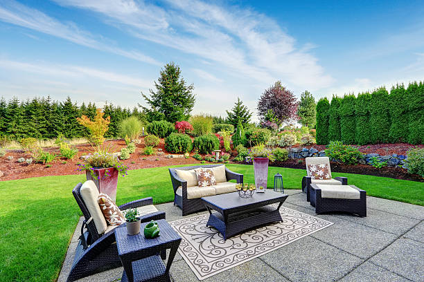 Impressive backyard landscape design with patio area Impressive backyard landscape design. Cozy patio area with settees and table yard grounds stock pictures, royalty-free photos & images