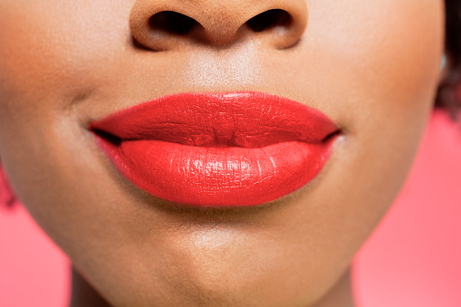 Close-up view of an African American woman's red lips over colored background