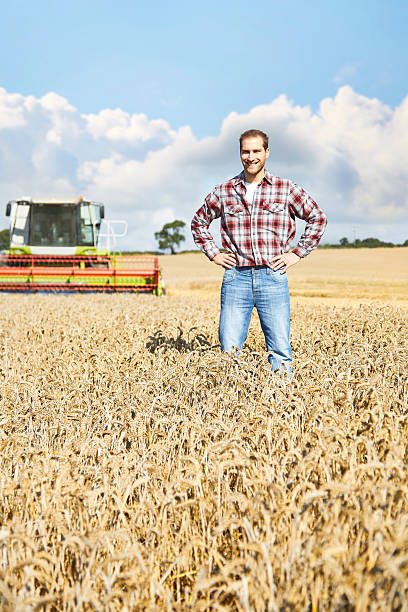 istock Proud farmer standing in field with combine harvester behind 520758359