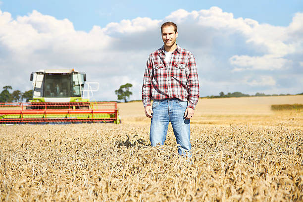 istock Proud farmer standing in field with combine harvester behind 520758391