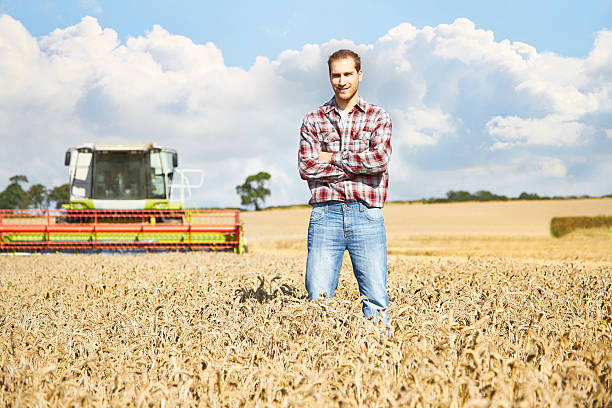 istock Proud farmer standing in field with combine harvester behind 520758433