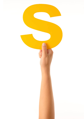 Woman hand holding yellow letter S. Isolated on white.