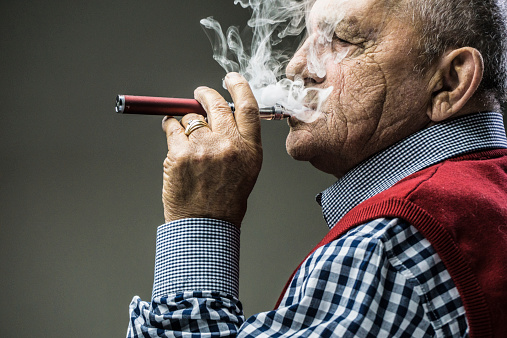 Older gentleman smoking an electronic cigarette.