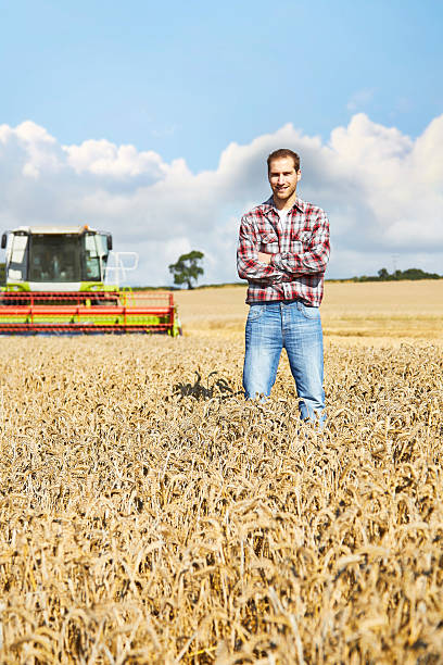 istock Proud farmer standing in field with combine harvester behind 520773441