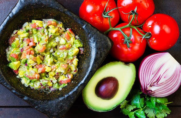 istock Guacamole in stone mortar and ingredients. Top view 520775468