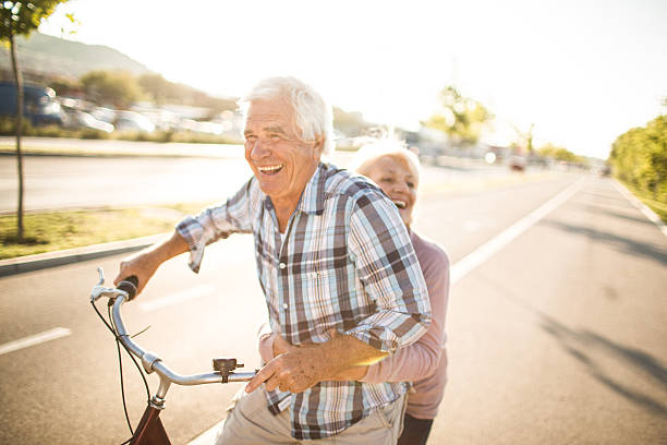 Confidence that lasts Smiling senior couple riding bicycles outdoors, enjoying their time together man 60s bicycle stock pictures, royalty-free photos & images