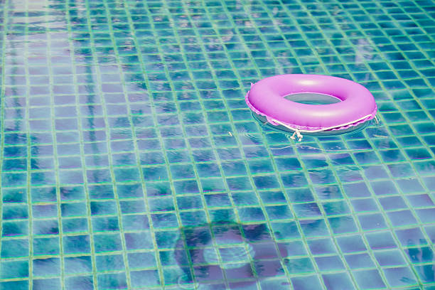 istock pink floating ring on blue water swimpool with waves reflecting 520776664